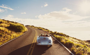 Happy Couple Driving on Country Road in Classic Vintage Sports Car