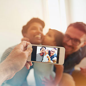 family smiling for picture being taken with phone