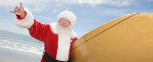man dressed as Santa with a surfboard