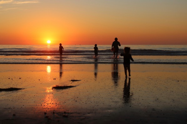 family running on the beach at sunset