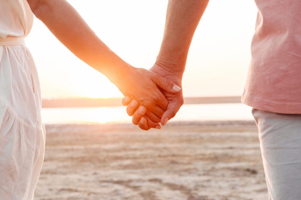 couple holding hands at the beach during sunset